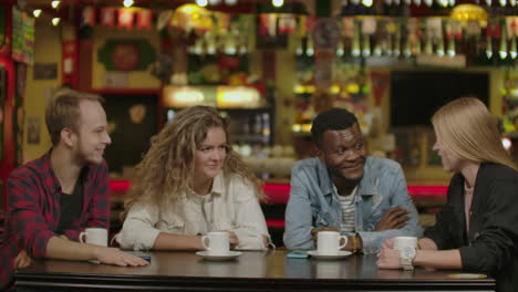 Happy-multiracial-young-people-friends-talking-laughing-at-group-meeting-sharing-cafe-table-diverse-students-drinking-coffee-having-fun-together-enjoy-multi-ethnic-friendship-pleasant-conversation